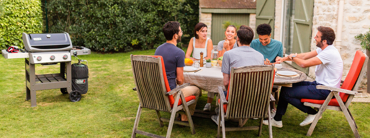 Παρέα απολαμβάνει γεύμα στον κήπο με ψησταριά BBQ υγραερίου στο εξοχικό.